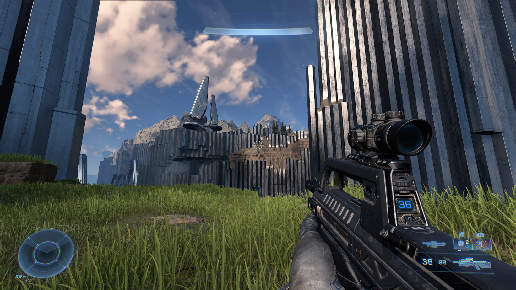 A nice vista of blue clouds, tall gray structures, and some green grass.